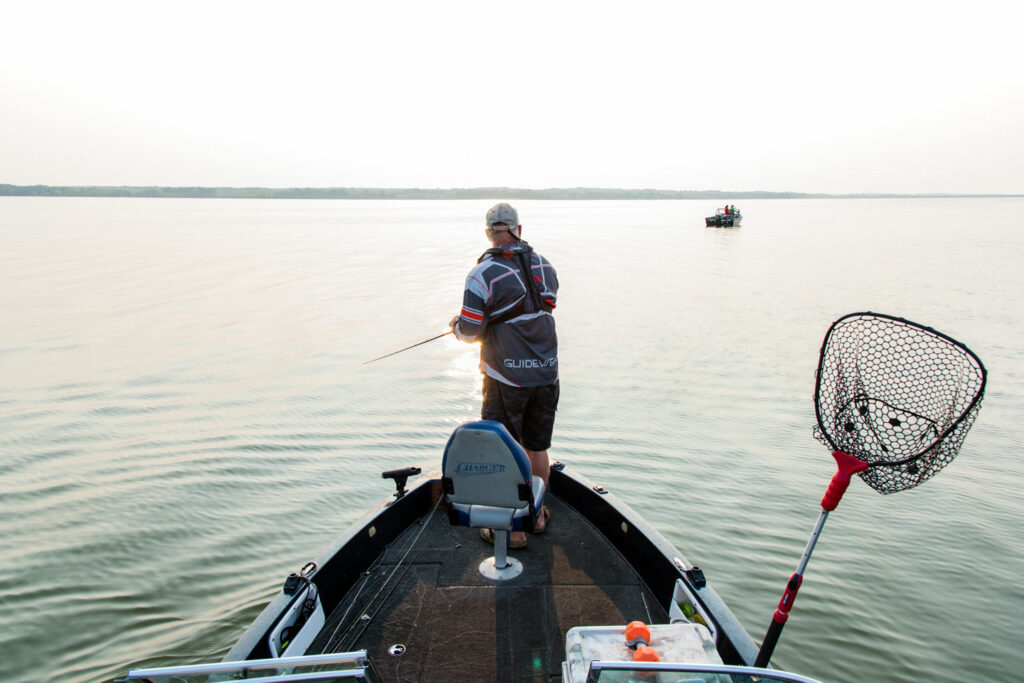 A man fishes from the bow of a boat