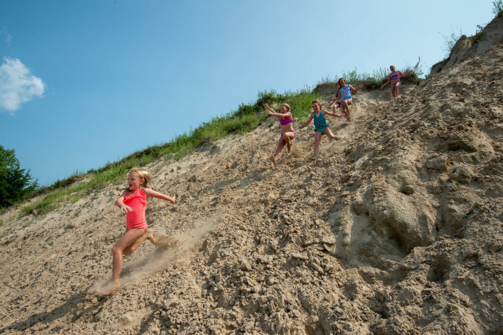 Kids run down a sandy hill