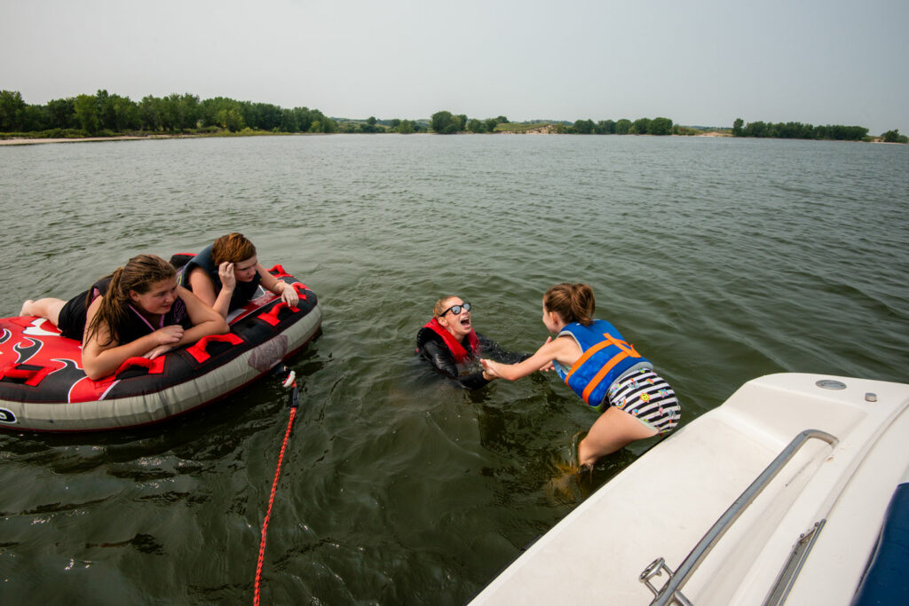 A girls jumps from a boat into a lake