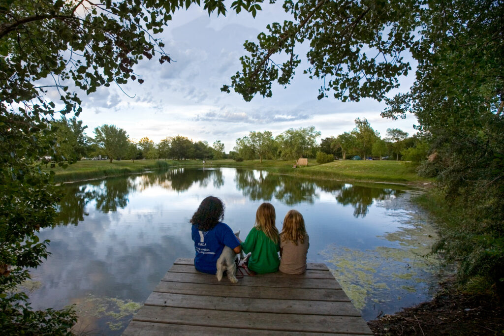 Three girls and a dog fish from a dock.