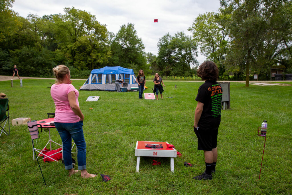 A woman throws a beanbag 