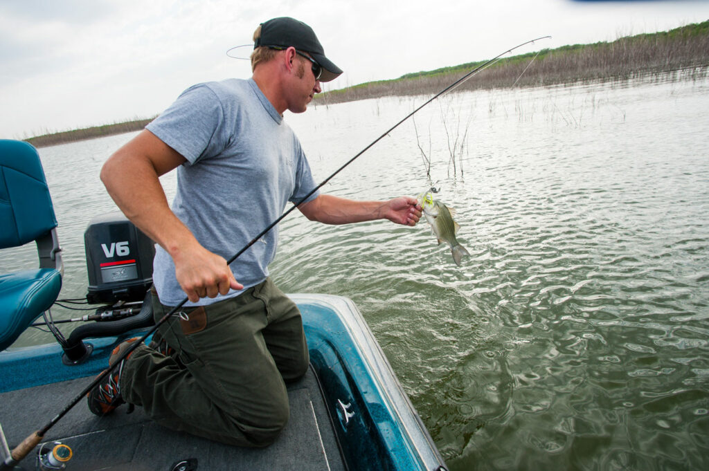 Man fishing from a boat on a lake.