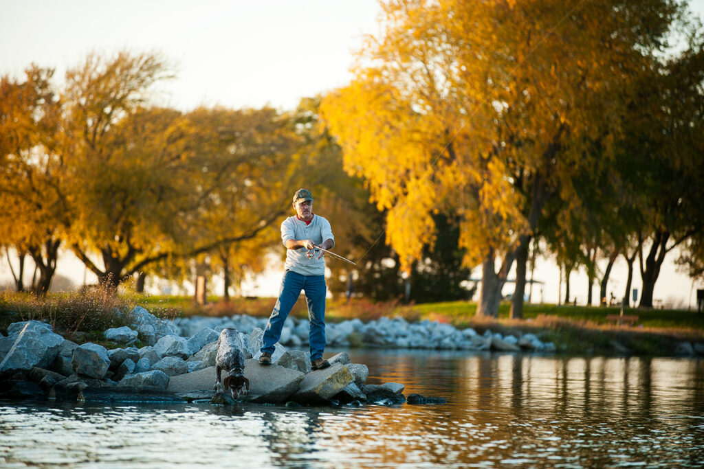 An angler fishes from a breakwater on a fall evening