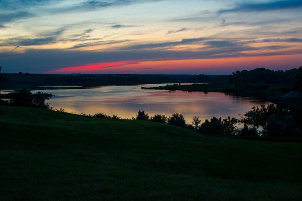 the sunset sky is reflected in the lake, creating a beautiful view