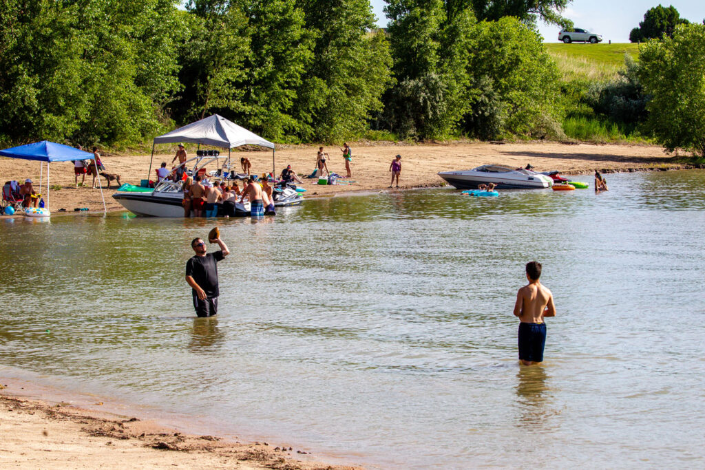 At the swim beach, two people in the water play catch with a football