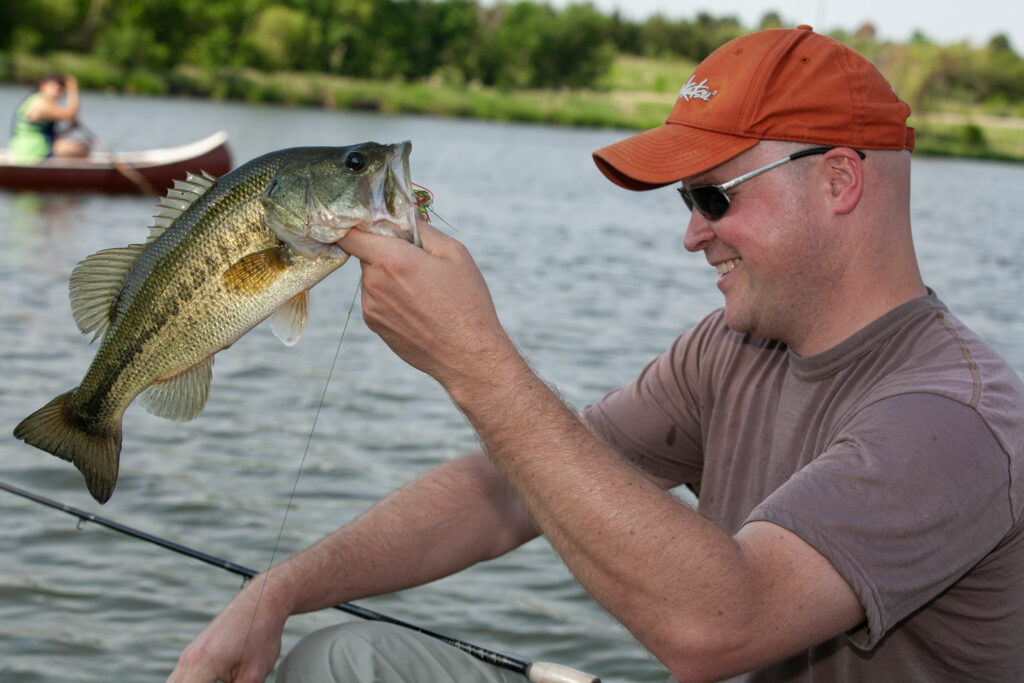 Man fishing for largemouth bass out of a lake.