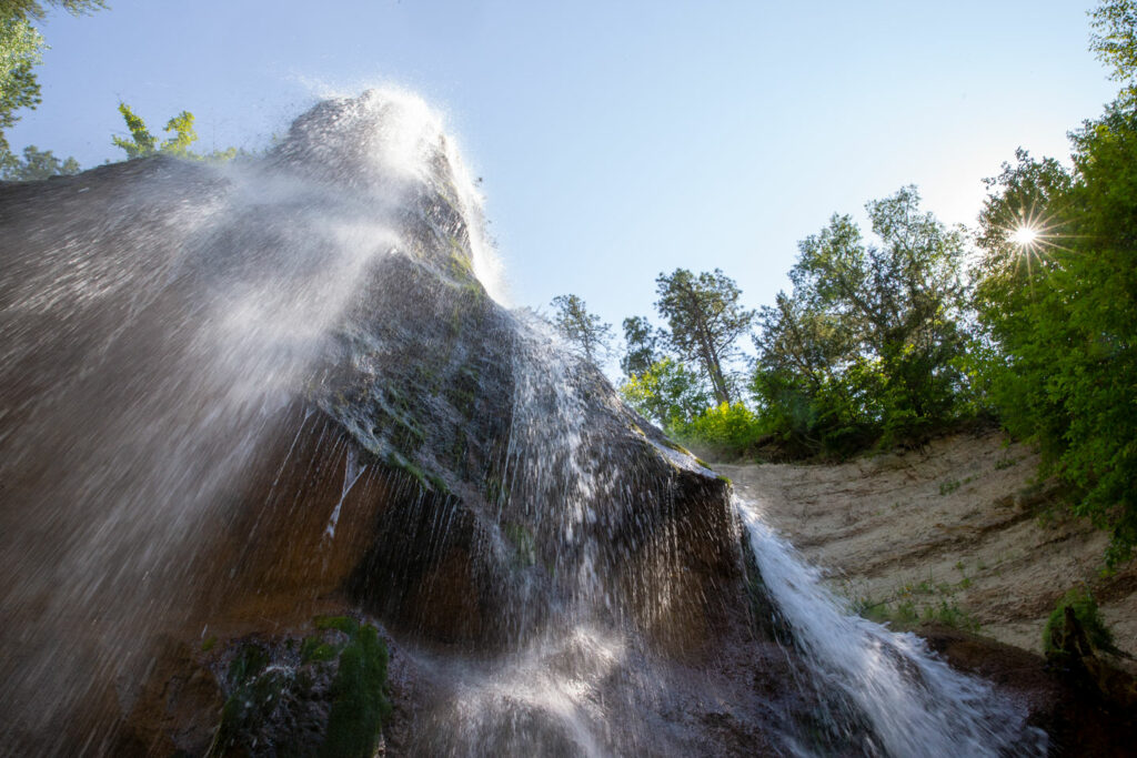 Water sprays over the bluff above.