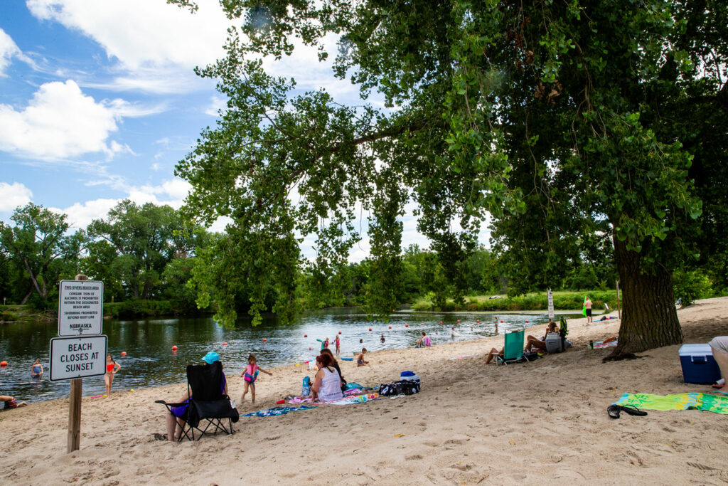 beach-goers sit in the sand and play in the water