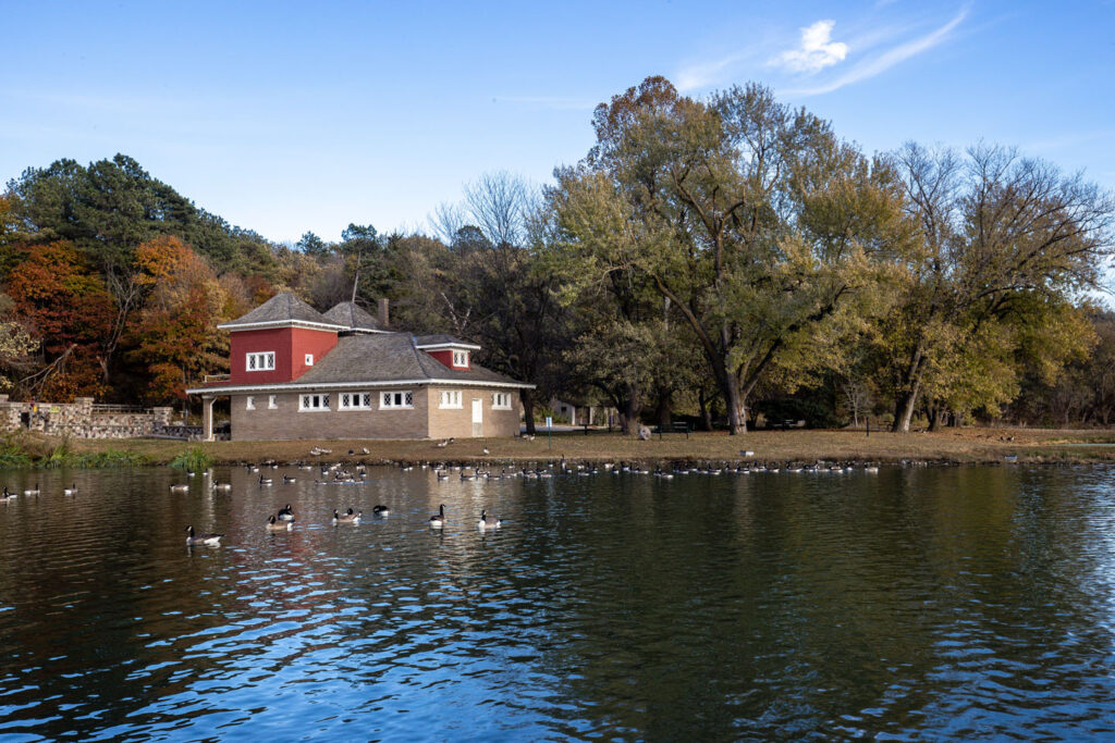 an old building is located by a lake where there are many geese 