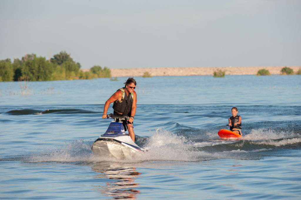 A  jet ski pulls a girl on a kneeboard