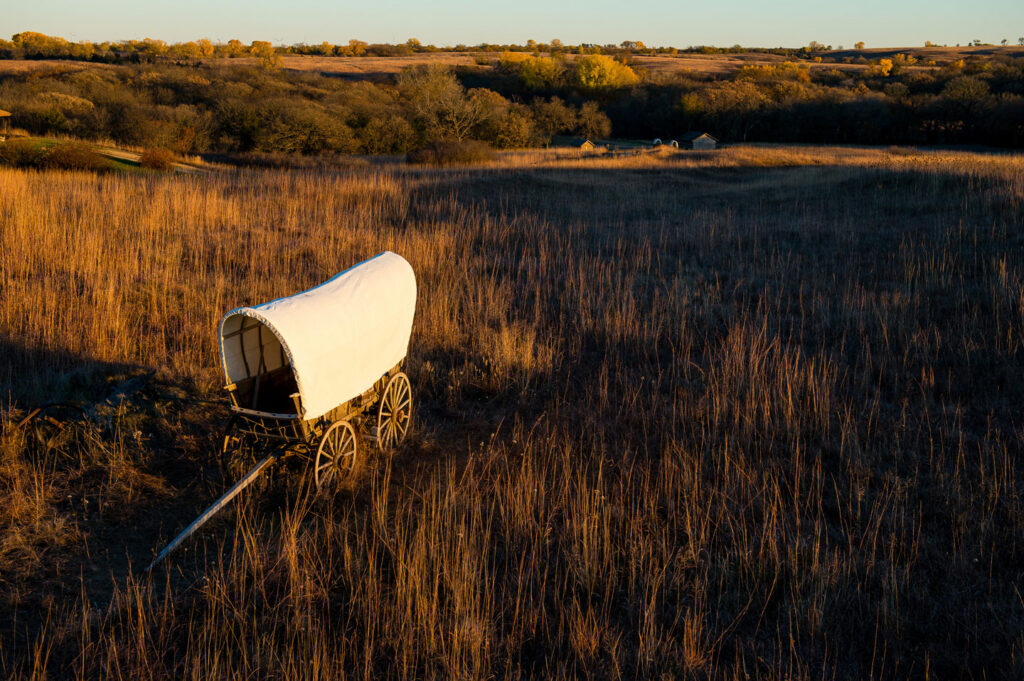 The white canvas of a covered wagons pops out against the golden prairie grasses at Rock Creek Station State Historical Park.