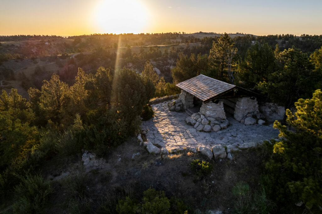 A stone picnic shelter reflects the setting sun's light off of its white stone.