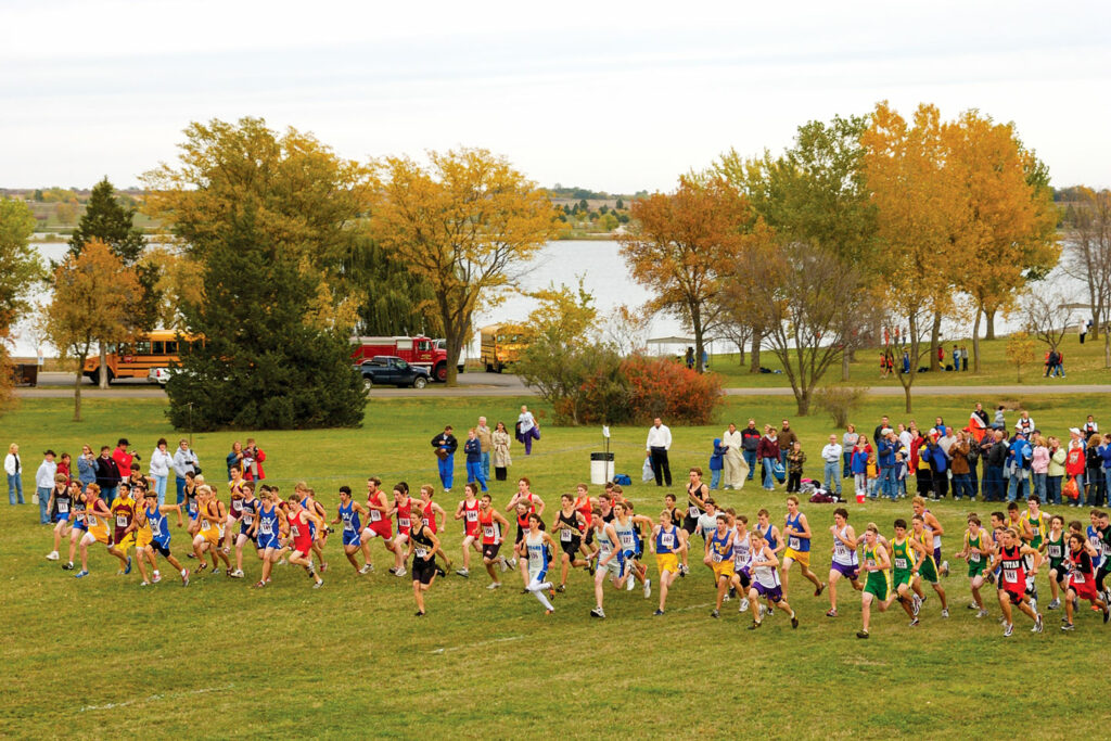 Cross country runners run on grass at Branched Oak SRA during fall.