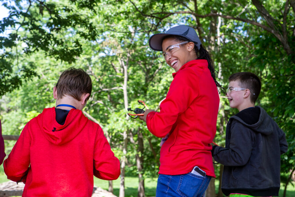 A female staff member laughs at her sling shot aim during the ancient hunting techniques portion of the Outdoor Explorer's camp.