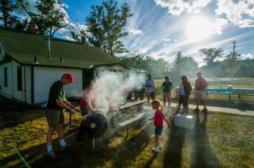 A family charcoal grills by their cabin