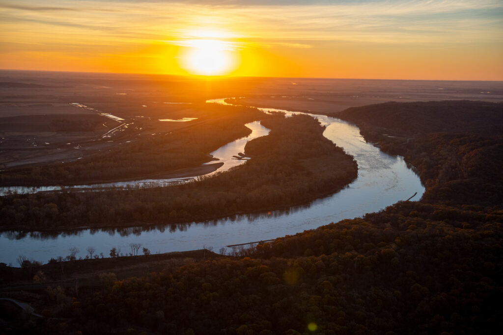 A river glistens under a rising sun