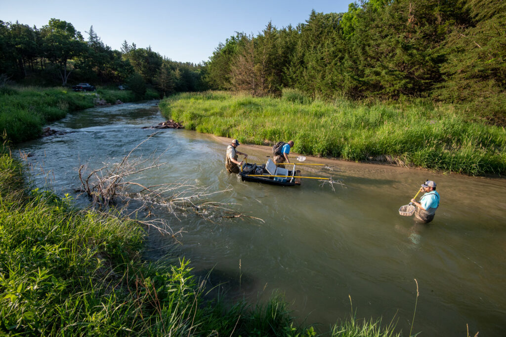 Three men standing in a creek