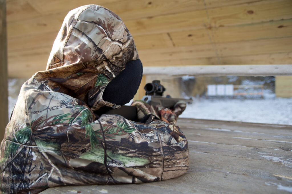 A girl sites in her rifle at a range.