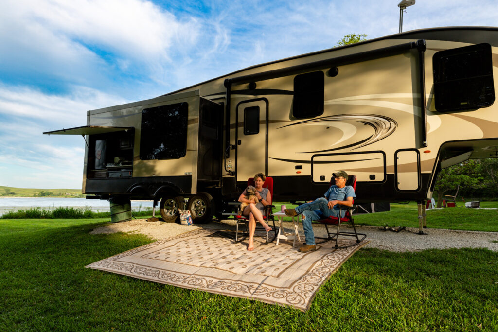 A man and woman with their dog in front of an RV