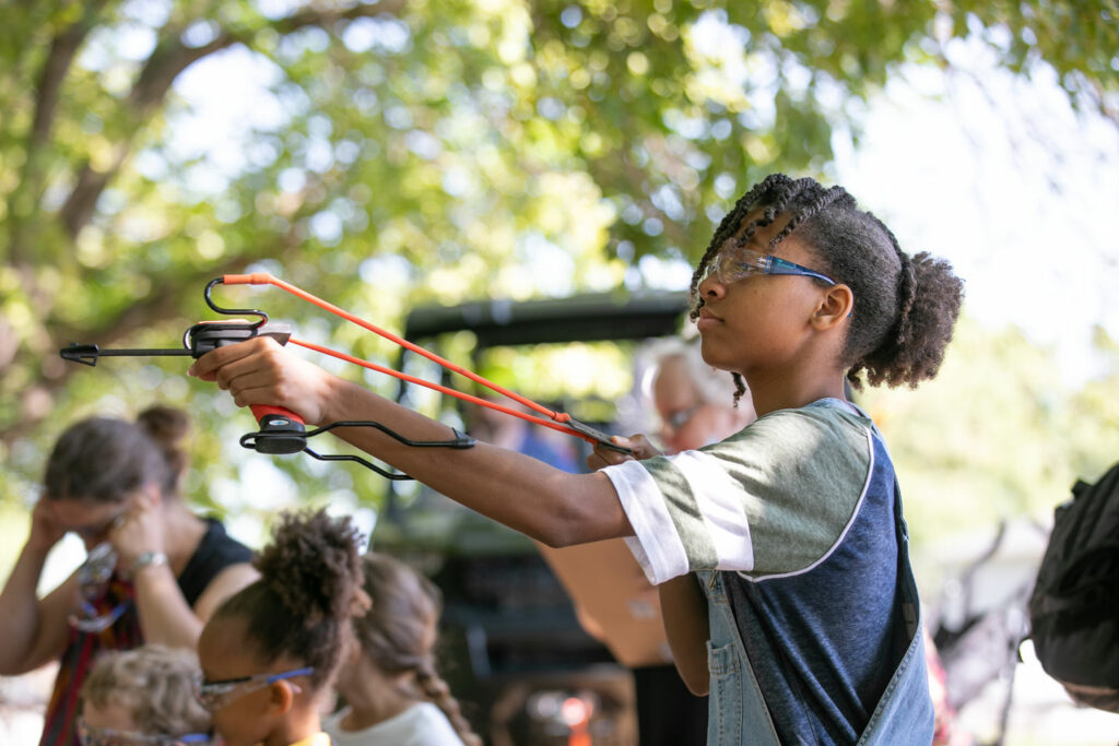 A boy shoots a slingshot