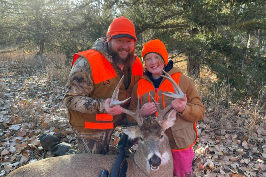 A father and daughter pose with a harvested whitetail buck deer.