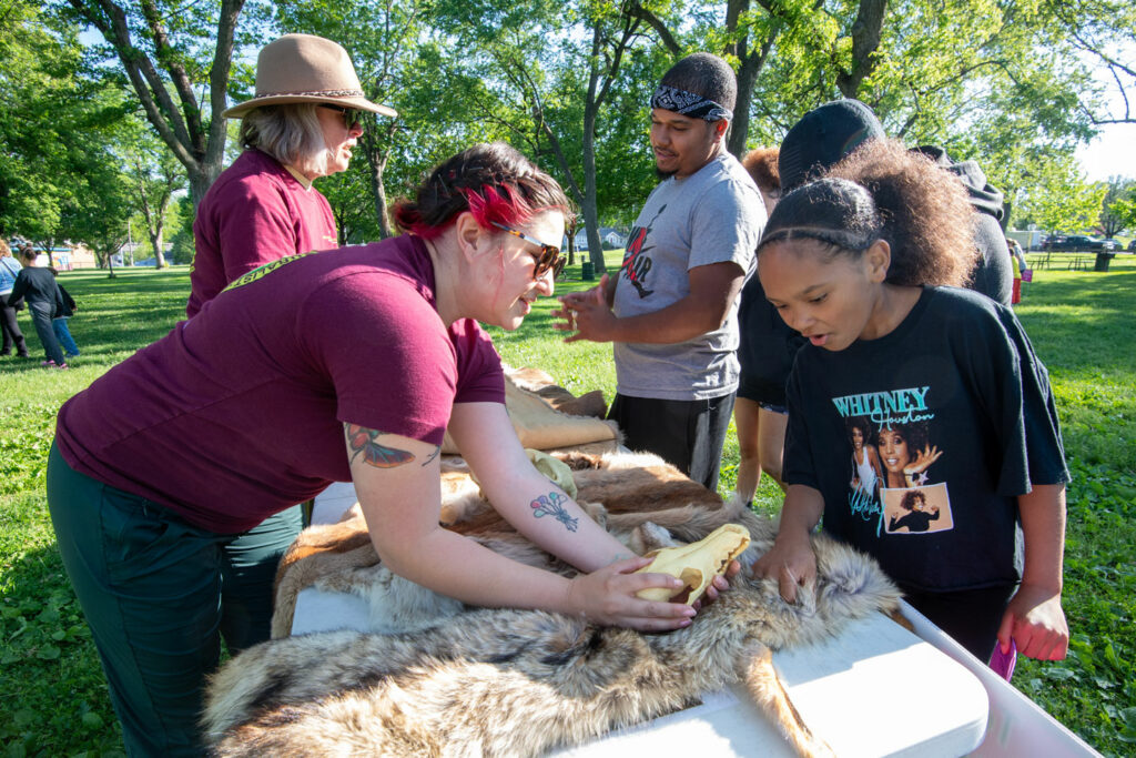 Two Nebraska master naturalists show a family some furs and skulls during a family nature night event.