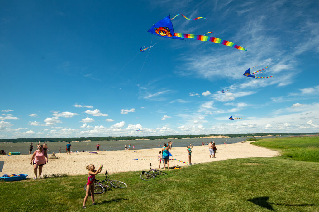 Visitors fly kites on the swim beach in the Weigand Area during Marina Days at Lewis and Clark Lake SRA in Knox County. Eric Fowler, June 15, 2019. Copyright NEBRASKAland Magazine, Nebraska Game and Parks Commission.