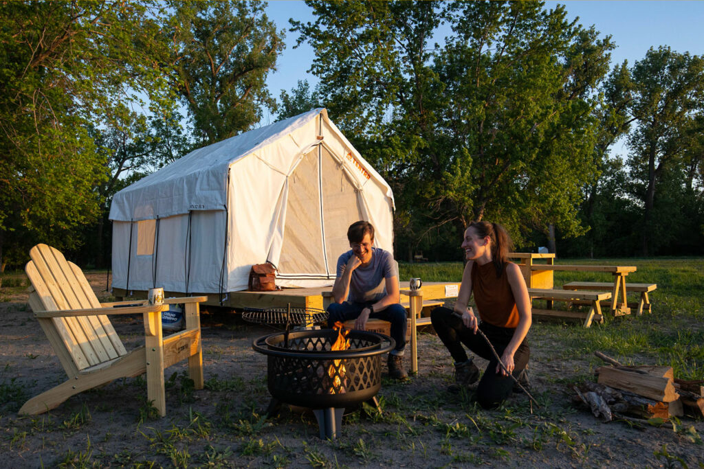 A couple tends to a fire pit at a Tentrr campsite at Louisville State Recreation Area.