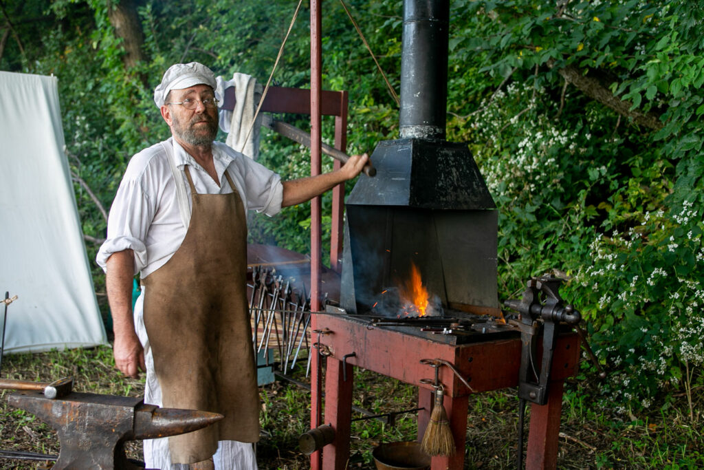 A volunteer blacksmith poses with his historical equipment at the Missouri River Outdoor Expo at Ponca State Park.