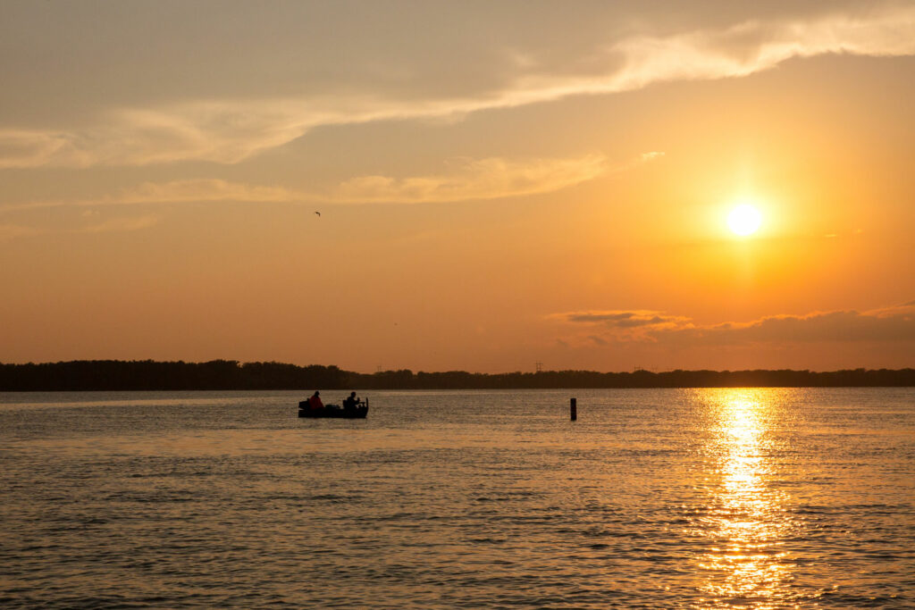 Two men in a boat fish into the evening as the sun goes down.