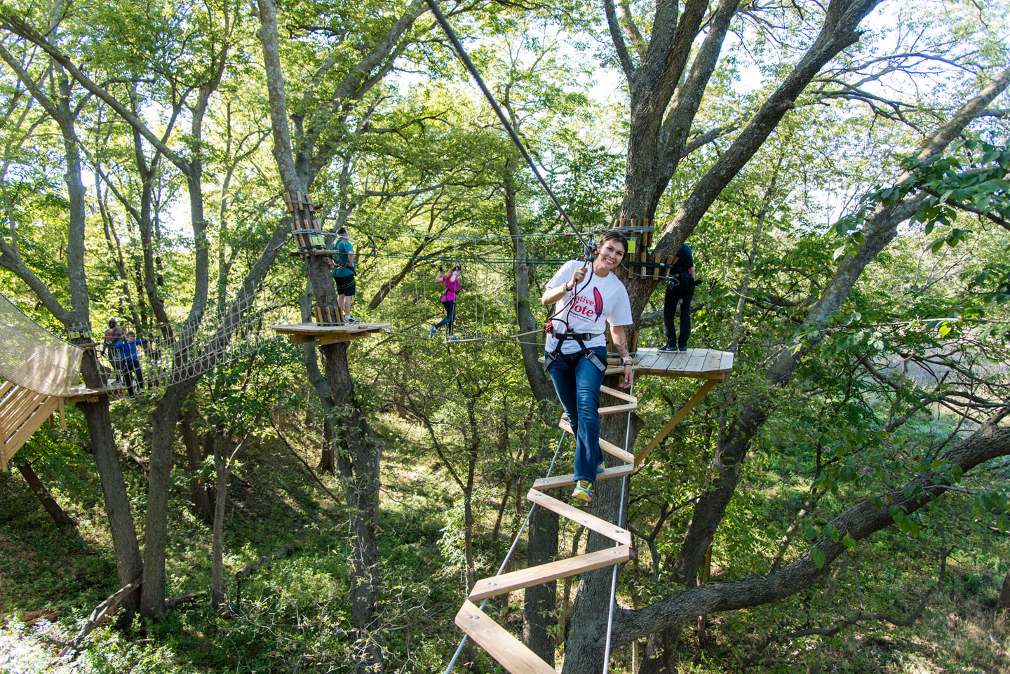 A woman climbs through the trees on  ziplines