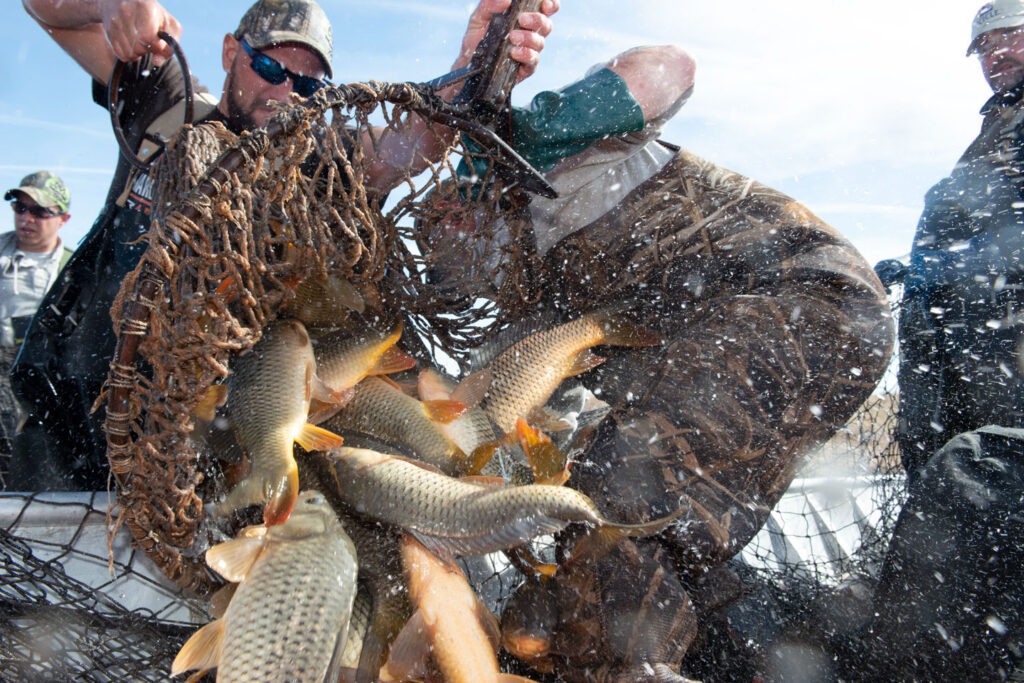 Men pull in a fishing net from a lake